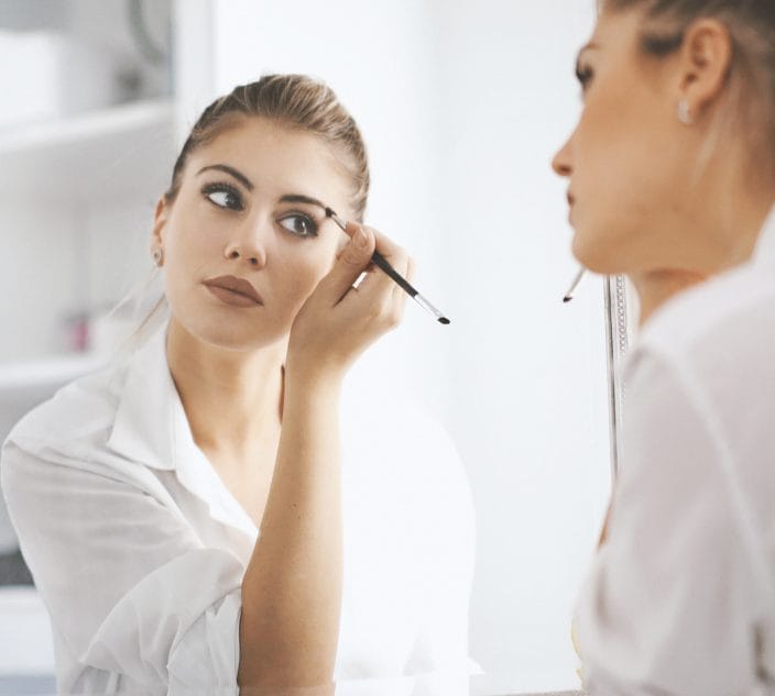 Young woman applies makeup.
