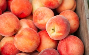 Picked peaches piled into a crate. OAS oral allergy syndrome fruit