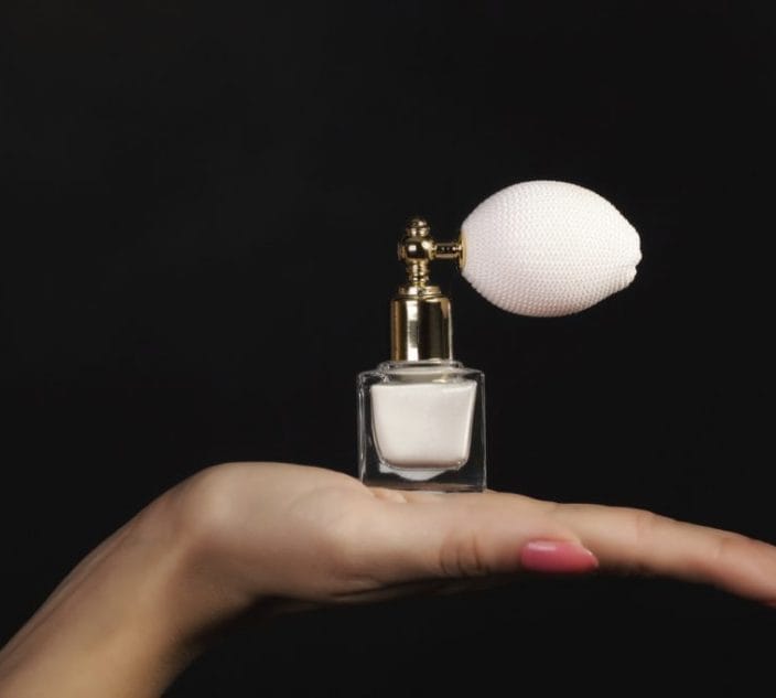 Fragrance sensitivity. Female hand with perfume bottle