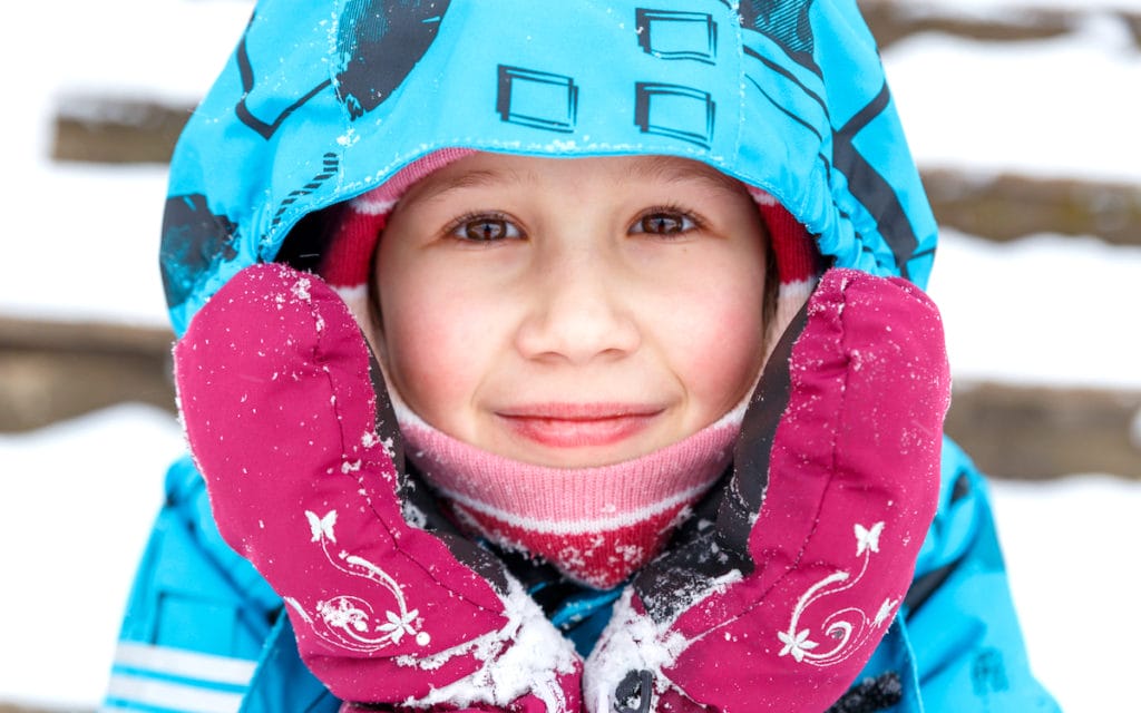Close-up portrait of bundled up child in the snow. Cold Urticaria.