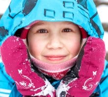 Close-up portrait of bundled up child in the snow.