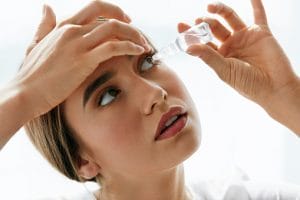Woman with eye allergy using eye drops.