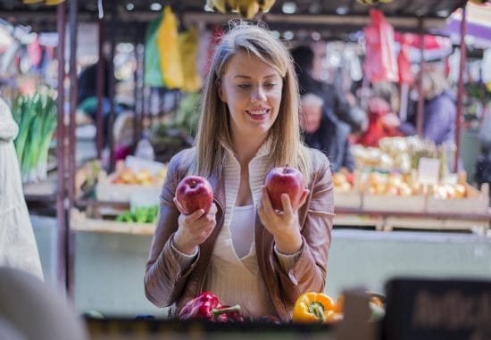 A woman looking at fruit - something to consider with oral allergy syndrome (OAS).