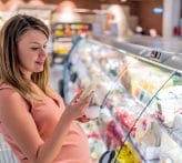 Pregnant mother decides what food to purchase at a grocery store.