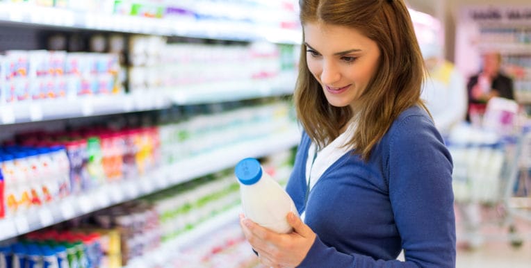 Young woman checking milk's labeling in supermarket.