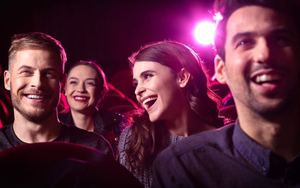 Young people laughing while watching a comedy skit. 