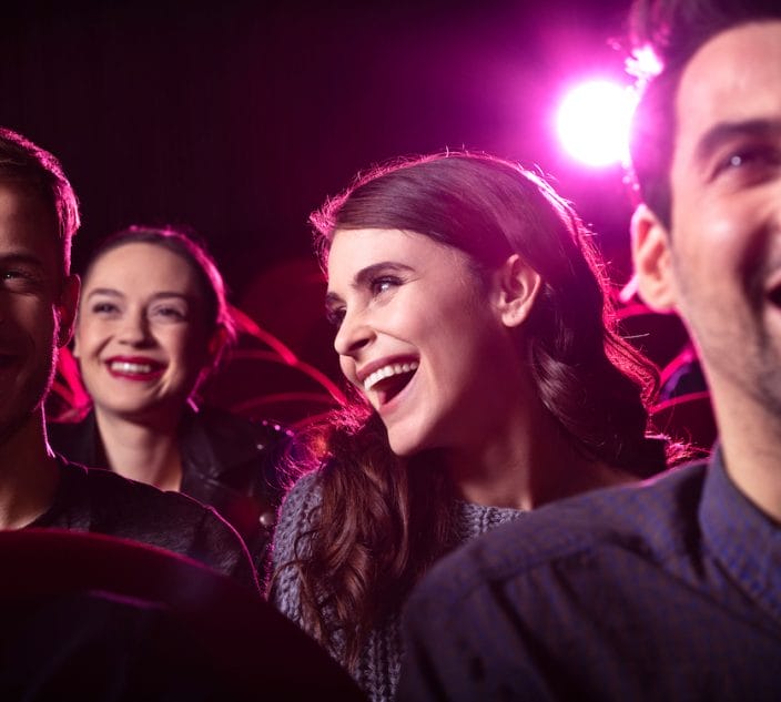 Young people laughing while watching a comedy show.