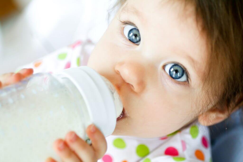 Close up of baby with bottle of formula.
