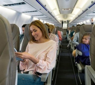 Woman on airplane looking at her phone.
