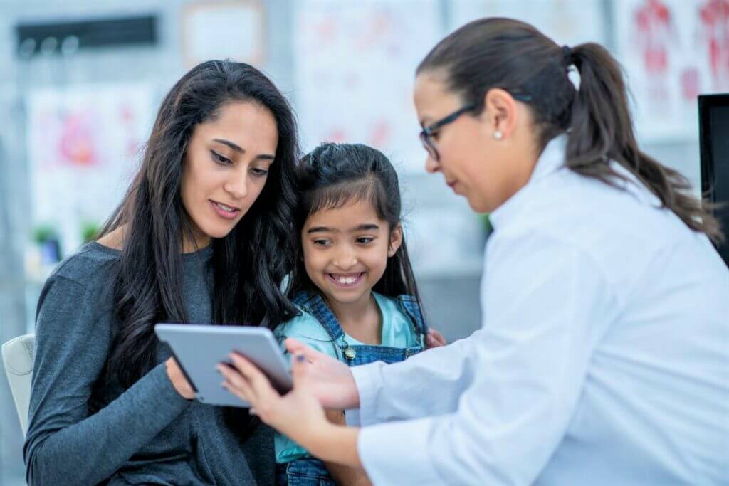 Doctor showing information on a tablet with mother and daughter. 

Allergist Stresses Safety for Milk and Egg Allergy 'Ladders'